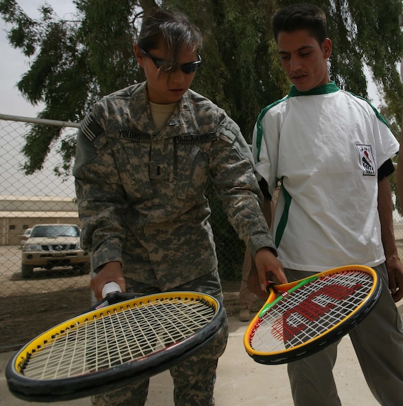 Air Force 1st Lt. Paige H. Young, from Pope's 43rd Contracting Squadron, shows an Iraqi Army soldier how to properly grip a tennis racket during a sports event culture at Iraqi Army base Area 4 May 17, which gave Iraqis an opportunity to experience a sport not common in Iraq. The event was held by Multi-National Corps – Iraq chaplains who frequently give servicemembers the opportunity to experience the local culture, while benefiting Iraqi citizens. (Courtesy of Multi-National Corps – Iraq Public Affiars Office)