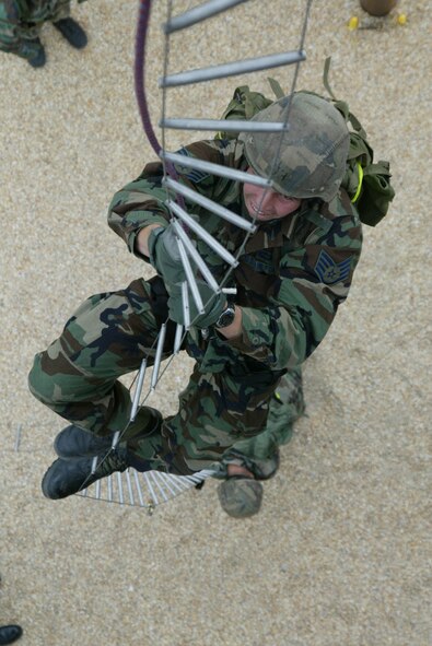 A combat control trainee negotiates the 60 foot caving ladder while carrying a 40-pound ruck sack on his back. (U.S. Air Force Photo)
