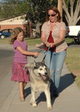 Heather Frazer and her daughter, Alex, walk their dog, Chewy. During hot weather exercise with pets should be limited to early morning or evening hours.(U.S. Air Force photo/Senior Airman Tiffany Trojca)