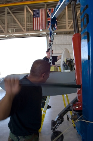 Senior Airmen Chestin Adaoag and Abigail Rice, background, both MQ-1 Predator avionics specialist assigned to the 432nd Aircraft Maintenance Squadron, hoist a ballast from the aircraft to secure a satellite here May 19, 2008.
(U.S. Air Force Photo by/Senior Airman Larry E. Reid Jr.)