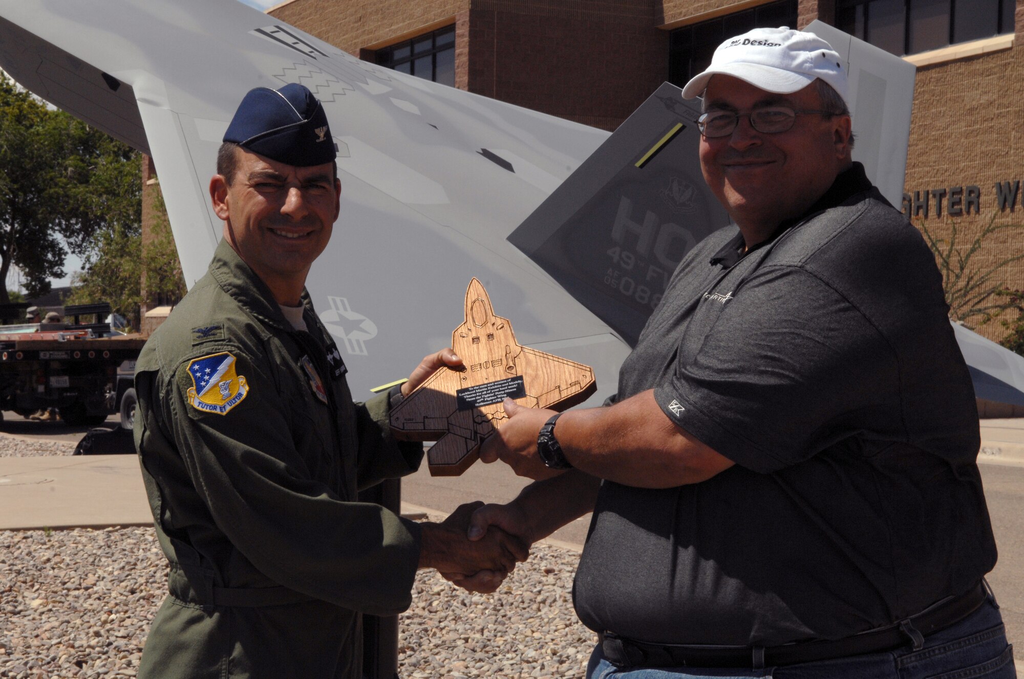 Col. Jeff Harrigian, 49th Fighter Wing commander, presents Tom Blakeney with an award in front of the newly displayed F-22A Raptor model on May 20 at Holloman Air Force Base, N.M. The award was presented to Mr. Blakeney who works at the Lockheed Martin model shop, and to the rest of the men and women who make up their team for all of their hard work. (U.S. Air Force photo/Airman Sondra M. Wieseler)