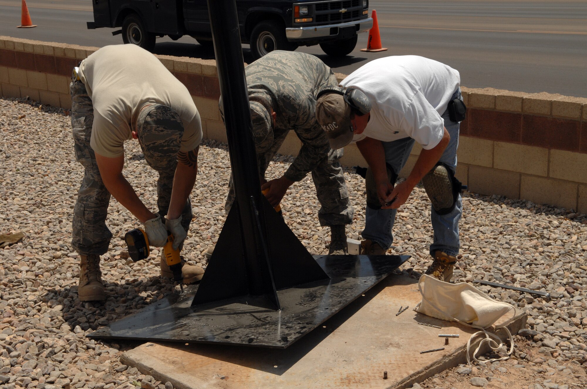 Members of the 49th Civil Engineer Squadron work diligently in the New Mexico heat to put up the stand on which the model F-22A Raptor will be displayed at the 49th Fighter Wing headquarters building at Holloman Air Force Base, N.M., May 20. The model, built by the Lockheed Martin model shop, was custom painted to Holloman?s markings. The model of the German Tornado, which has stood in front of the building for years, also received a new paint job. (U.S. Air Force photo/Airman Sondra M. Wieseler)