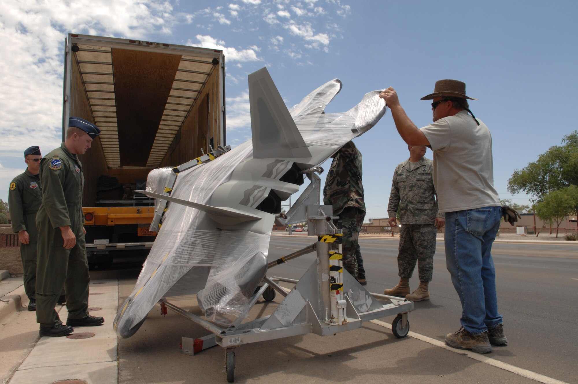 Members of Team Holloman unload a 375-pound model of an F-22A Raptor from the back of a delivery truck at the 49th Fighter Wing headquarters building at Holloman Air Force Base, N.M., May 20. The F-22A model will replace the F-117A Nighthawk model that was displayed in front of the building, along with the model of a German Tornado. (U.S. Air Force photo/Airman Sondra M. Wieseler)