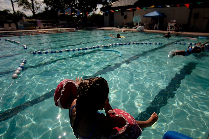 Abigail Lee slides into the base pool May 26. The base pool is now open Tuesday - Friday, 6-7 a.m. for free lap swimming with no charge and Tuesday - Sunday, 12-5 p.m. for recreational swimming. Abigail is the 5-year-old daughter of Roy and Alesha Lee. (U.S. Air Force photo/Senior Airman Nicholas Pilch)