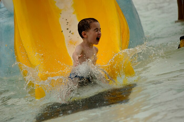 Anthony Saienni glides down the slide at the base pool May 24. The base pool is now open Tuesday - Friday, 6-7 a.m. for free lap swimming with no charge and Tuesday - Sunday, 12-5 p.m. for recreational swimming.  Anthony is the 3-year-old son of Martin and Amber Saienni.  (U.S. Air Force photo/Senior Airman Nicholas Pilch)