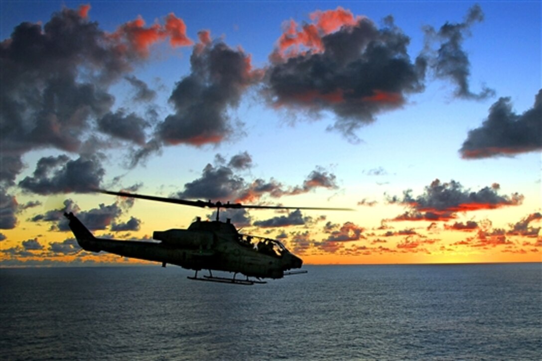 A Marine AH-1A Super Cobra fast-attack helicopter passes the amphibious assault ship USS Tarawa during sunset over the Pacific Ocean, May 21, 2008. The USS Tarawa is on a scheduled deployment to the U.S. 7th Fleet area of responsibility operating in the western Pacific and Indian oceans.   