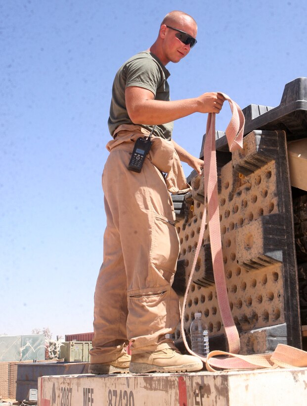 During an unloading of a re-supply line, Lance Cpl. Eric M. Gilbert, 21, a warehouse clerk with Headquarters and Service Company, 2nd Light Armored Reconnaissance Battalion, Regimental Combat Team 5, unfastens a crate full of items at Camp Korean Village, Iraq, May 29. Each day the two Marines running the supply warehouse, Gilbert, from Lebanon, Ohio, and Lance Cpl. Joseph M. McDonough, 25, from Staten Island, N.Y., receive new shipments to be unloaded, sorted and distributed to requesting unit.