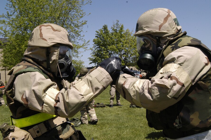 (Left) Tech. Sgt. Jennifer Grega helps Master Sgt. Harold Jeffries fasten on his protective gloves.  The two Airmen won first place in the timed Mission Oriented Protective Posture gear donning competition. (U.S. Air Force photo/Airman 1st Class Shen-Chia Chu)