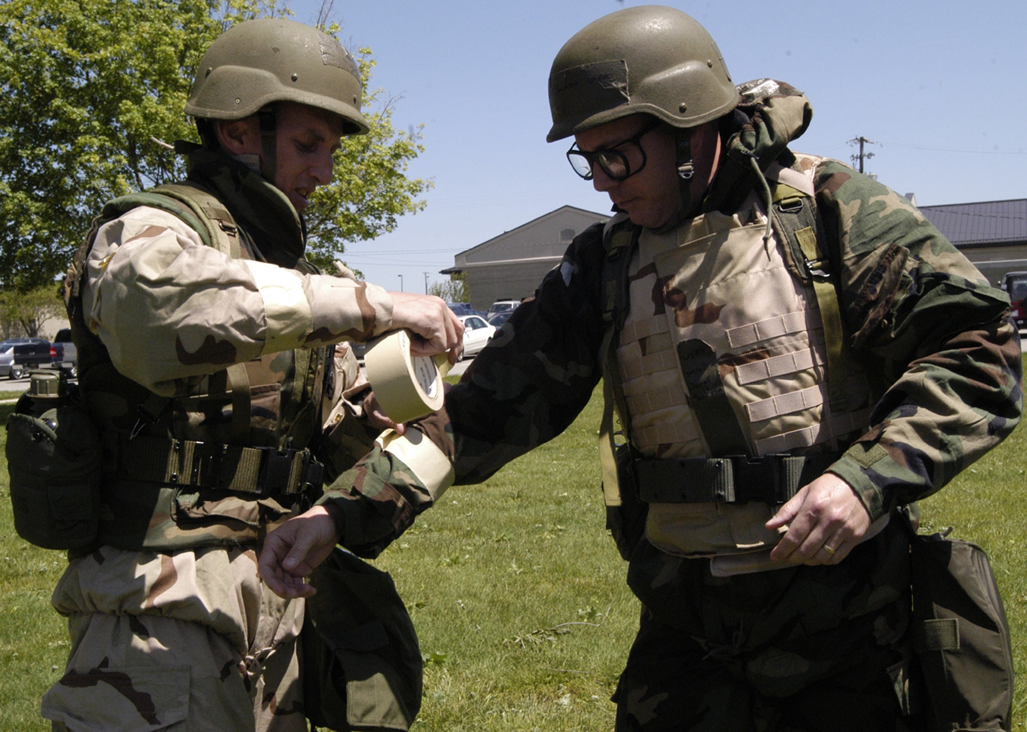 (Left) Master Sgt. Jonathan Redfern places simulated M-9 tape on Senior Master Sgt. Darrell Sanderson’s sleeves during the 436th OSS timed MOPP gear donning competition.  During exercises and wartime, it's essential Airmen work together to safeguard each other and accomplish the mission. (U.S. Air Force photo/Airman 1st Class Shen-Chia Chu)