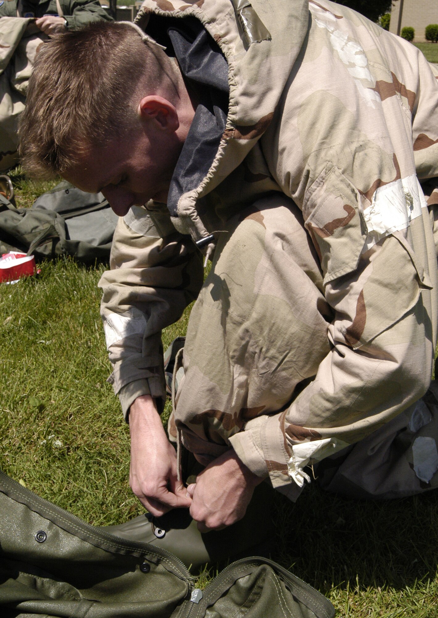 1st Lt. Eric Larson, buttons up his boots as he practices with other 436th OSS Airmen in donning Mission Oriented Protective Posture gear. The 436th OSS held a timed MOPP gear donning competition to practice for the upcoming operational readiness inspection. (U.S. Air Force photo/Airman 1st Class Shen-Chia Chu)