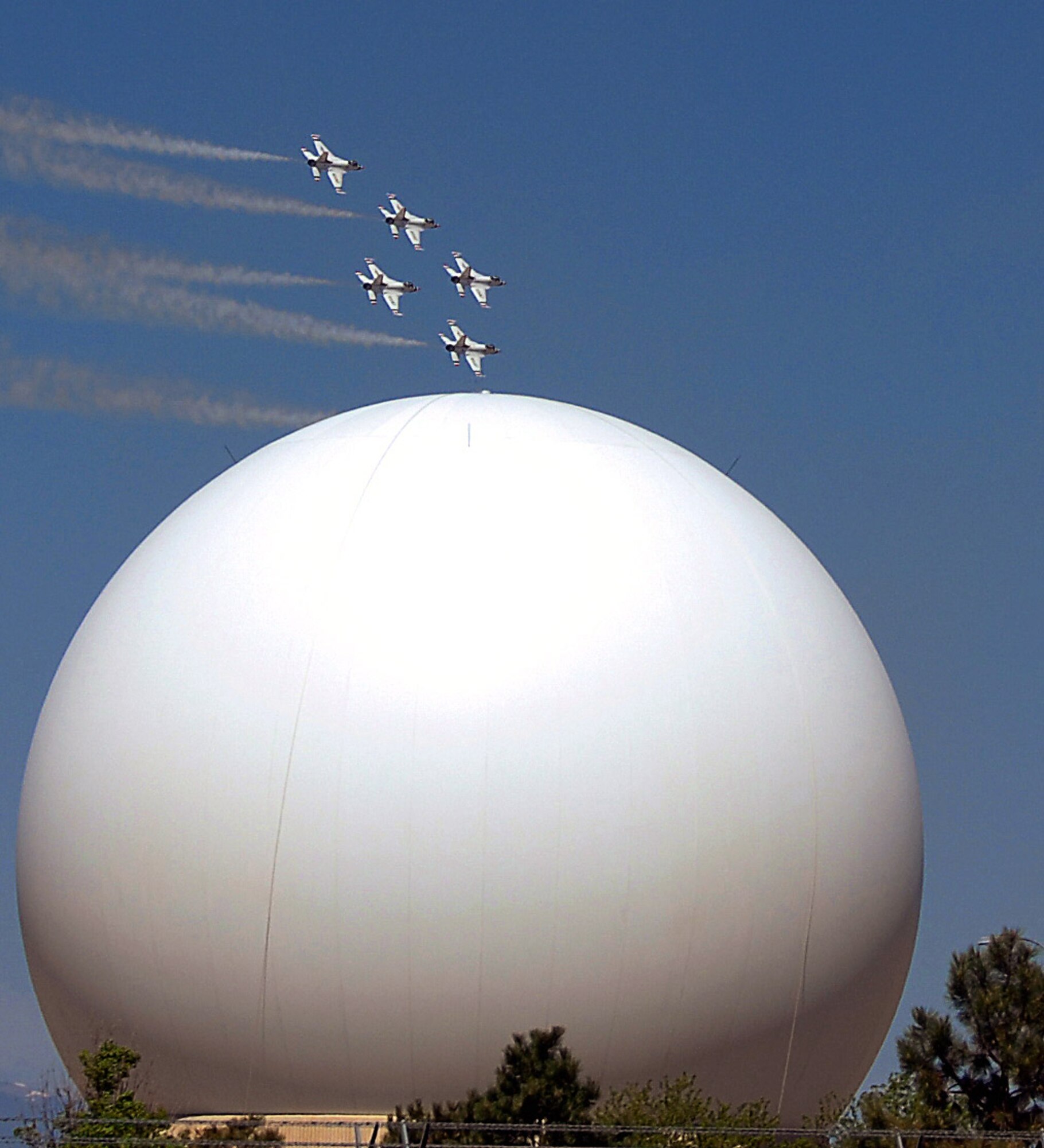 The U.S. Air Force Thunderbirds fly over Schriever Air Force Base, Colo., May 25 as they prepare for an aerial demonstration at the U.S. Air Force Academy graduation May 28. In the foreground is one of two Air Force Satellite Control Network radomes at the Colorado Tracking Station at Schriever AFB.  (U.S. Air Force photo/Duncan Wood)