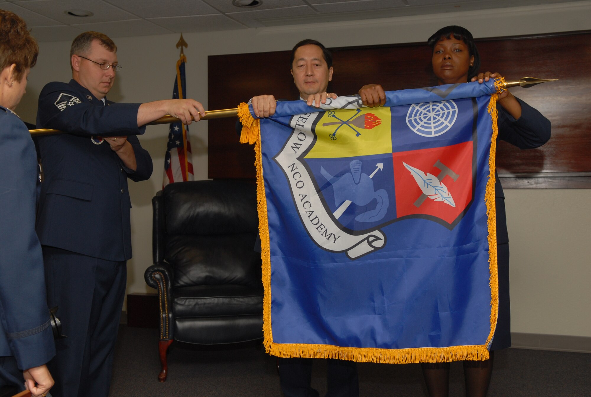 Master Sgt. Russell Pember holds the Goodfellow NCO Academy flag as it is furled by Col. Thomas Klincar, College of Enlisted Professional Military Education commander, and Chief Master Sgt. Edy Agee, GNCOA commandant, during the inactivation ceremony May 28. (U.S. Air Force photo by Staff Sgt. John Barton)