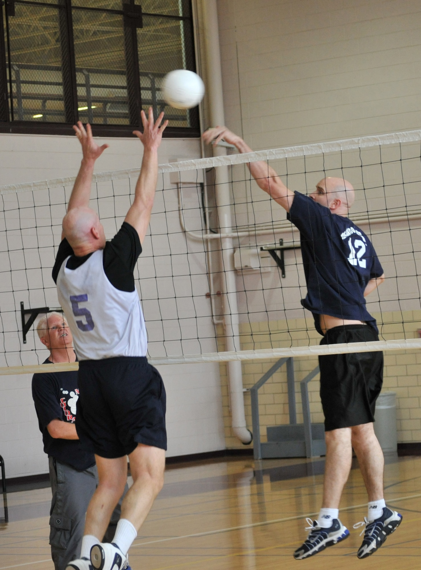 NORAD/NORTHCOM’s Tim Lundberg, right, taps the ball over the outstretched arms of AFSPC/All’s Rusty Lorenz during action May 22 at the Peterson Fitness and Sports Center intramural volleyball competitive championship game. (U.S. Air Force photo by Walt Johnson)