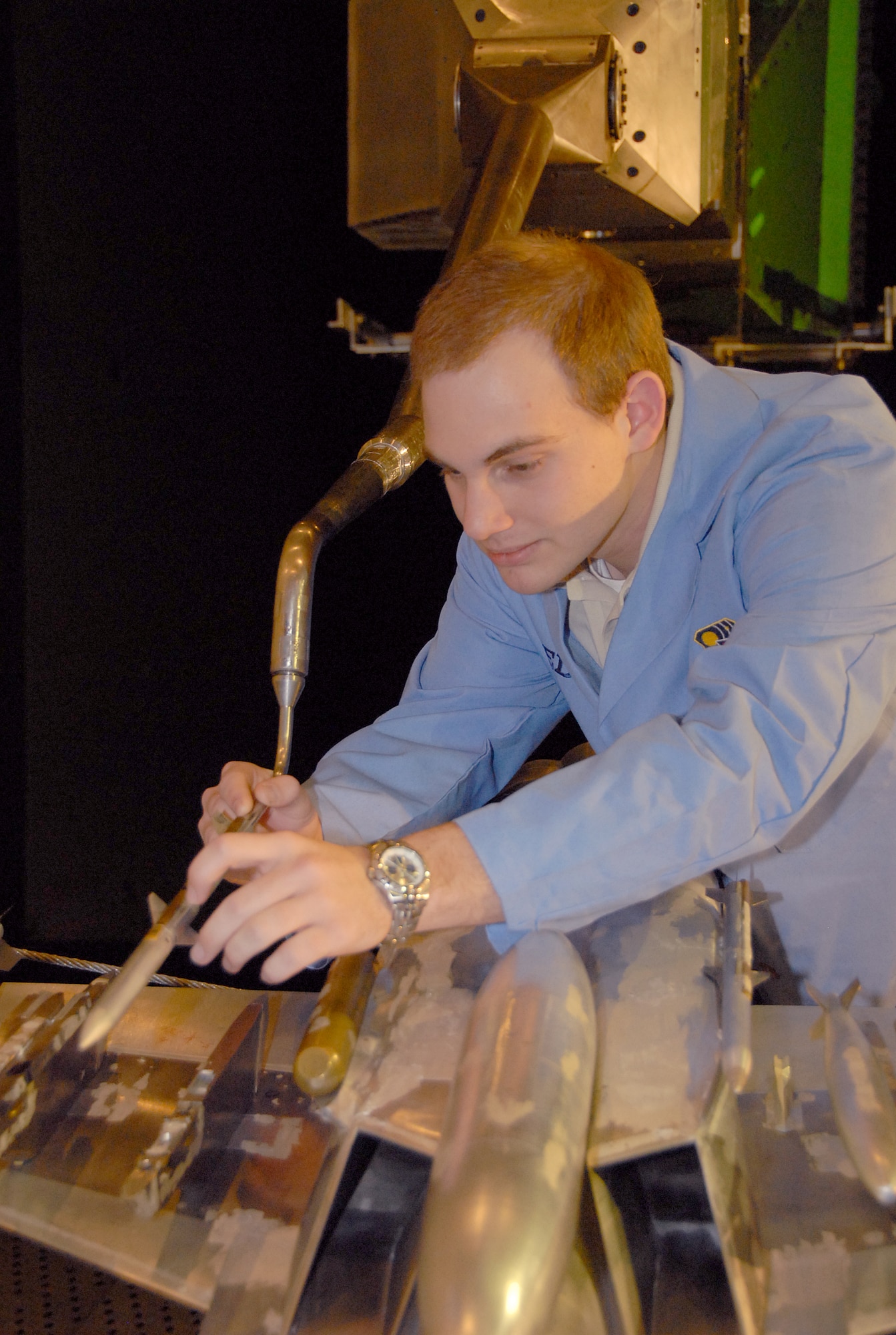 Adam Burt, a co-op student working with Aerospace Testing Alliance, inspects the 1/10-scale models of the sting-mounted AIM-120C store and F/A-18E/F aircraft during a break in store separation testing inside AEDC’s 16-foot transonic wind tunnel. ATA is the support contractor for the center. The ongoing testing marks the 13th entry of the Super Hornet for store separation testing in 16T. The data from the testing goes into a database and leads to flight testing. (Photo by David Housch)