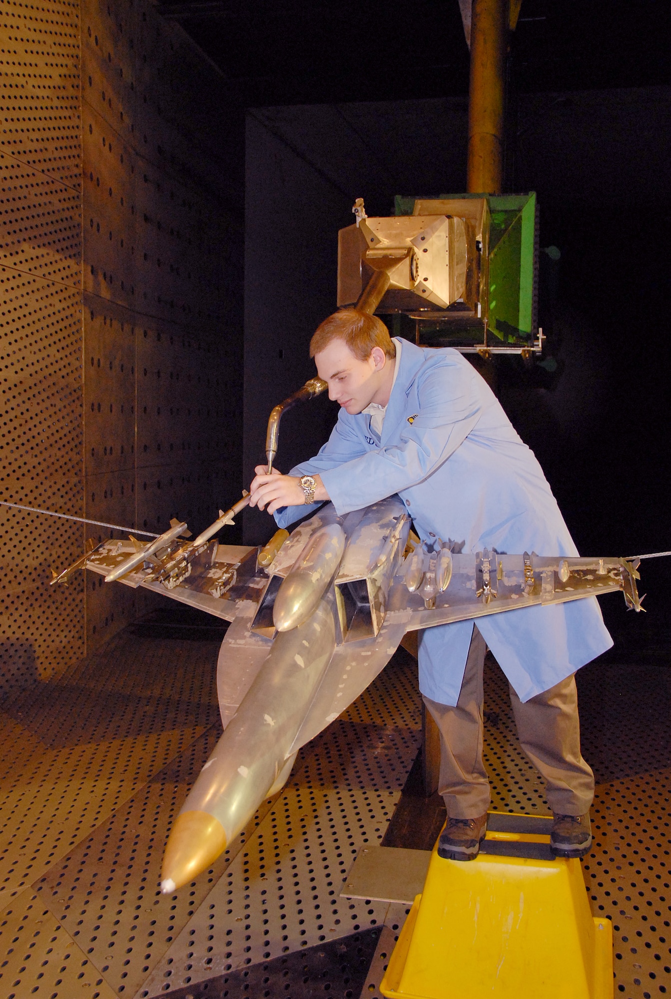 Adam Burt, a co-op student working with Aerospace Testing Alliance, inspects the 1/10-scale models of the sting-mounted AIM-120C store and F/A-18E/F aircraft during a break in store separation testing inside AEDC’s 16-foot transonic wind tunnel. ATA is the support contractor for the center. The ongoing testing marks the 13th entry of the Super Hornet for store separation testing in 16T. The data from the testing goes into a database and leads to flight testing. (Photo by David Housch)