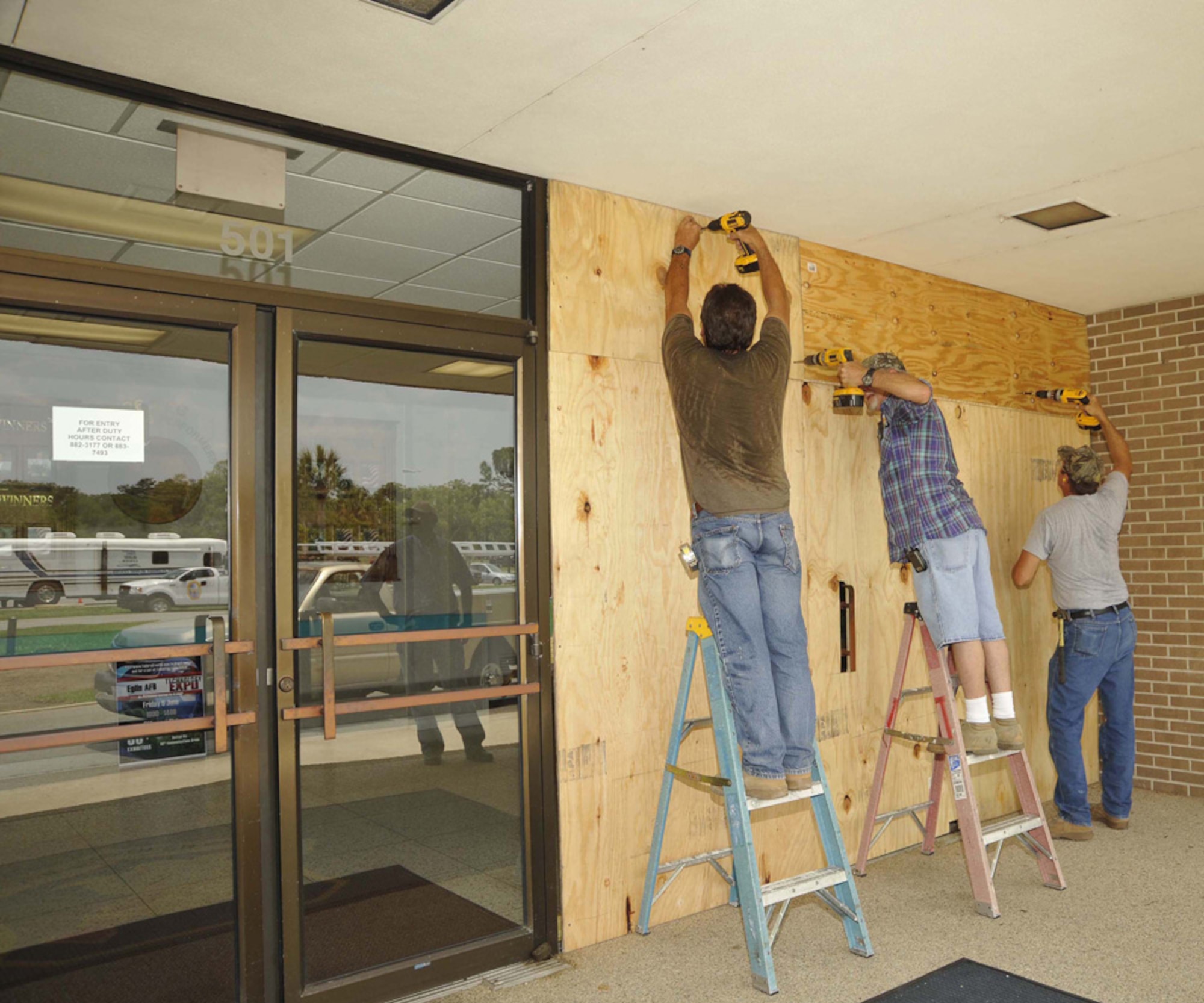 A crew from the 796th Civil Engineer Squadron installs plywood over the front entrance of the CE headquarters building.  The squadron was showing its capability during the Hurricane Lynda exercise. (USAF photo by Bruce Hoffman)
