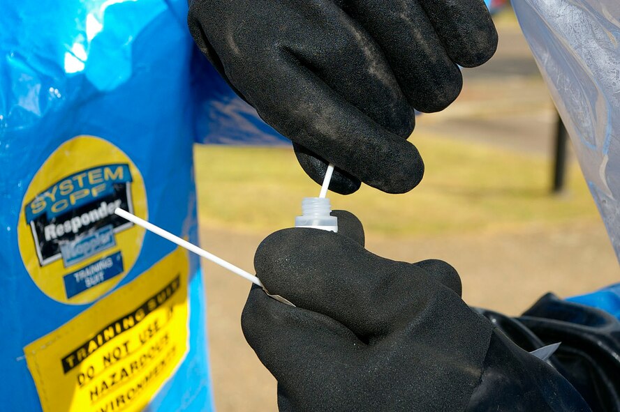 Senior Airman Neal Clark and Airman 1st Class David Norris, both 100th CES Readiness and Emergency Management, break off a swab sample and put it into a container before adding a liquid to test for chemical agents. (U.S. Air Force photo by Karen Abeyasekere) 