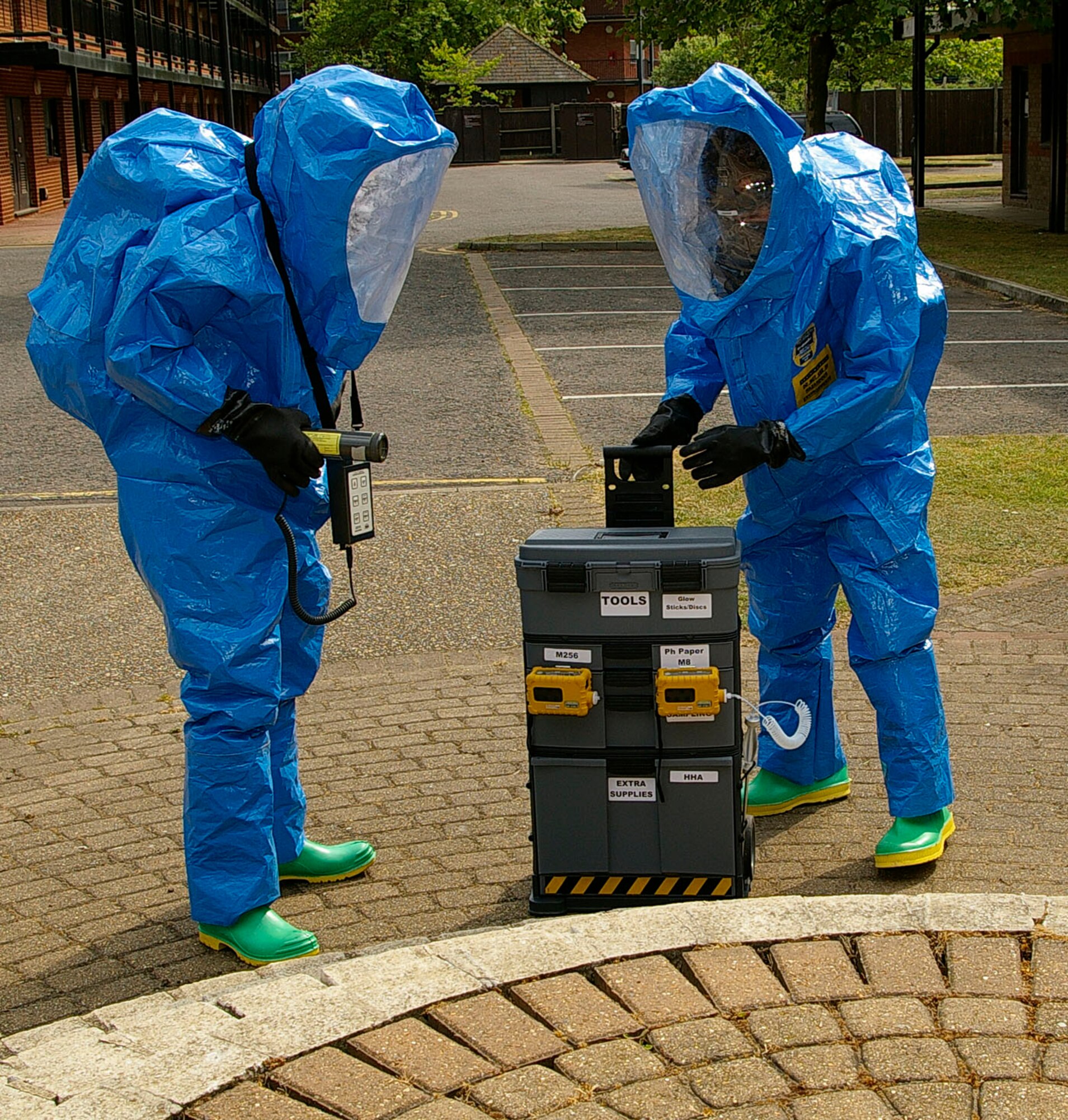 Senior Airman Neal Clark, left, and Airman 1st Class David Norris, both 100th CES Readiness and Emergency Management, prepare to collect samples from the white powder around the simulated suspicious package to check for radiological, biological and chemical agents. (U.S. Air Force photo by Karen Abeyasekere)