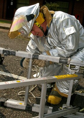 Firefighter Mark Peskett ties ladders together to form a decontamination area to collect water, should it be needed, during the exercise May 23. (U.S. Air Force photo by Karen Abeyasekere)