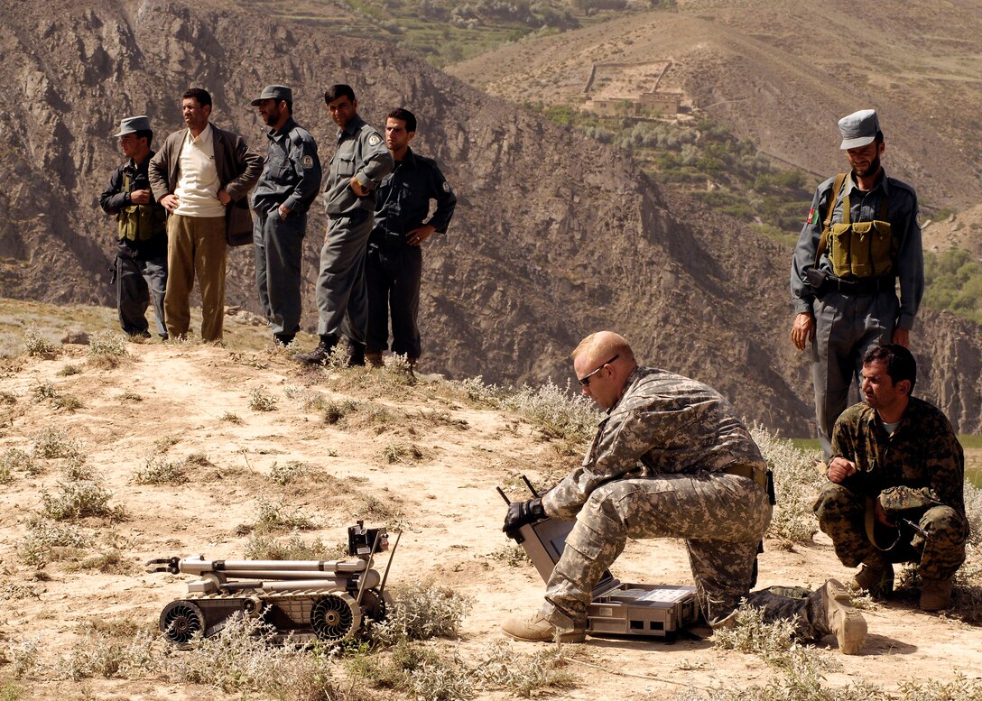 Staff Sgt. Jason Snow sends a Pacbot to an incident site in Panjshir Province, Afghanistan while local authorities watch. Two 107 mm rockets on timer were found aimed at a coalition forward operating base and then destroyed. (U.S. Air Force photo/Master Sgt. Demetrius Lester)