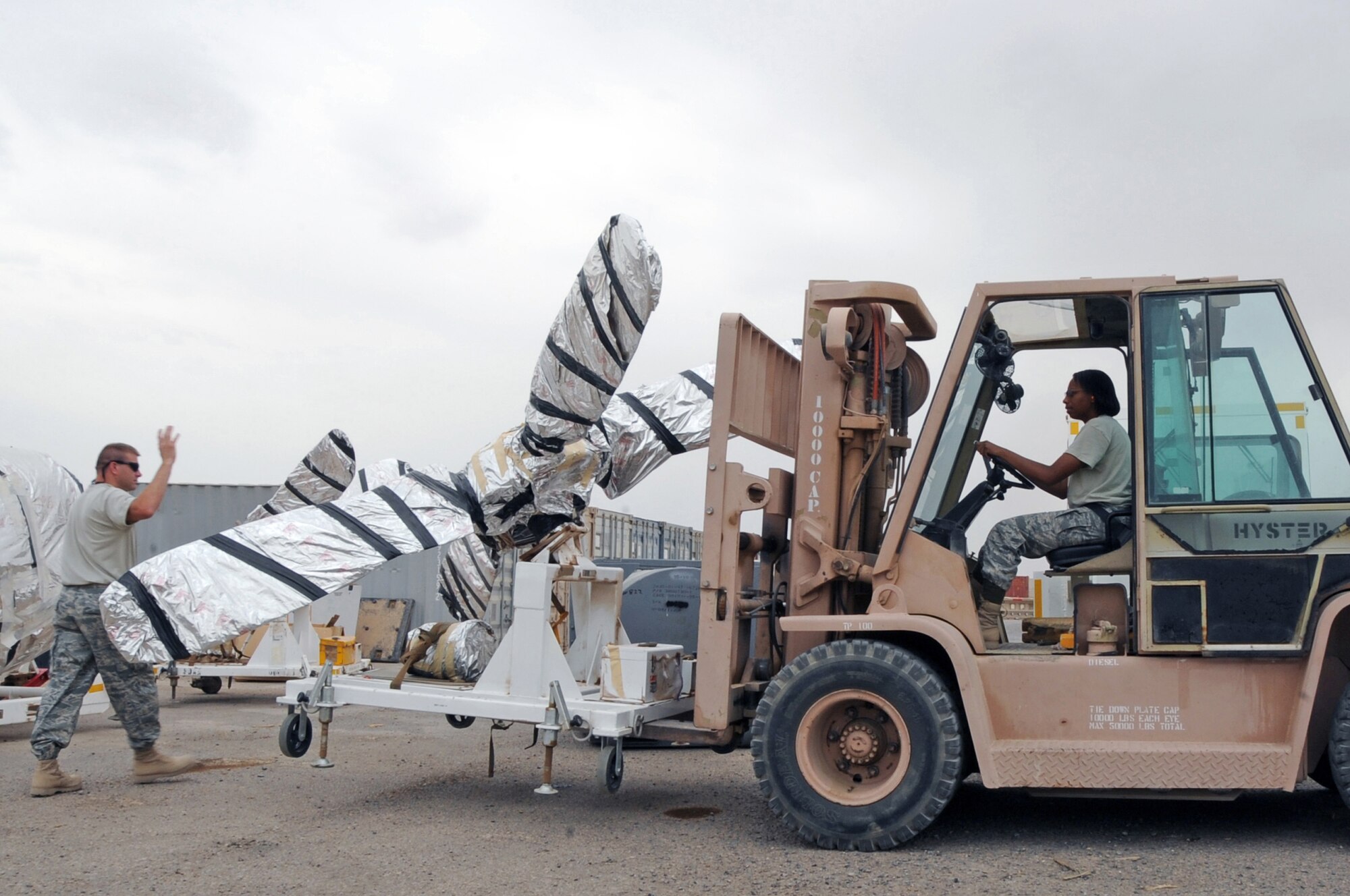ALI BASE, Iraq -- Tech. Sgt. Loren Hare, noncomissioned officer in charge of outbound cargo, signals Staff Sgt. Sapira Walker, hazardous cargo specialist, on the placement of a Navy P-3 Orion propeller May 30. The Traffic Management Office is responsible for preparing, packaging, shipping and receiving of all outbound cargo here. Sergeant Hare and Walker are deployed to the 407th Expeditionary Logistics Readiness Squadron from Luke AFB, Ariz. (U.S. Air Force photo/Tech. Sgt. Sabrina Johnson)