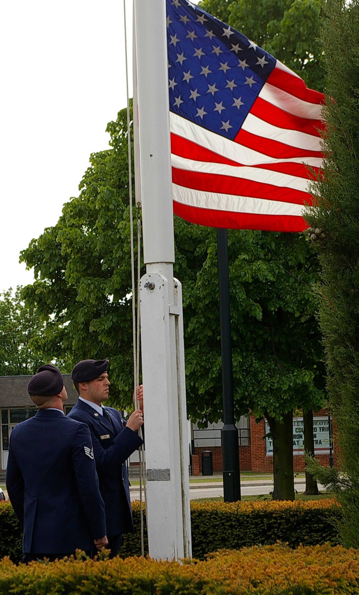 Airman 1st Class James Joyce, right, 100th Security Forces Squadron, slowly lowers the American flag as Staff Sgt. Clinton Petit, also 100th SFS, stands by waiting to assist in folding it May 15. The servicemen were part of a four-person Color Guard during the retreat ceremony performed as part of National Police Week events. (U.S. Air Force photo by Karen Abeyasekere)