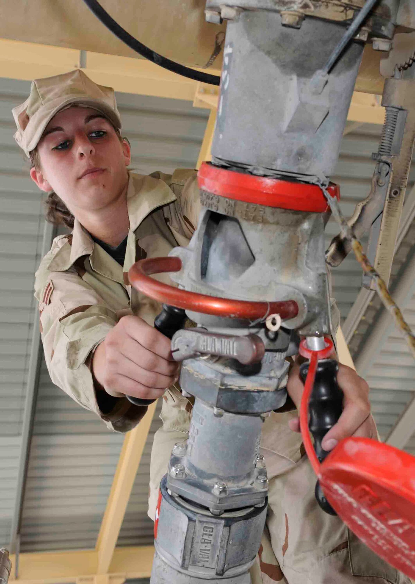 Airman 1st Class Megan Cotton, 379th Expeditionary Logistics Readiness Squadron, hooks up a pantograph fueling system to the bottom loader of an R11 fuel truck here May 28. Airman Cotton uses the new system to fill 5,800 gallons of jet fuel in about 15 minutes. (U.S. Air Force photo/ Tech. Sgt. Johnny Saldivar.)