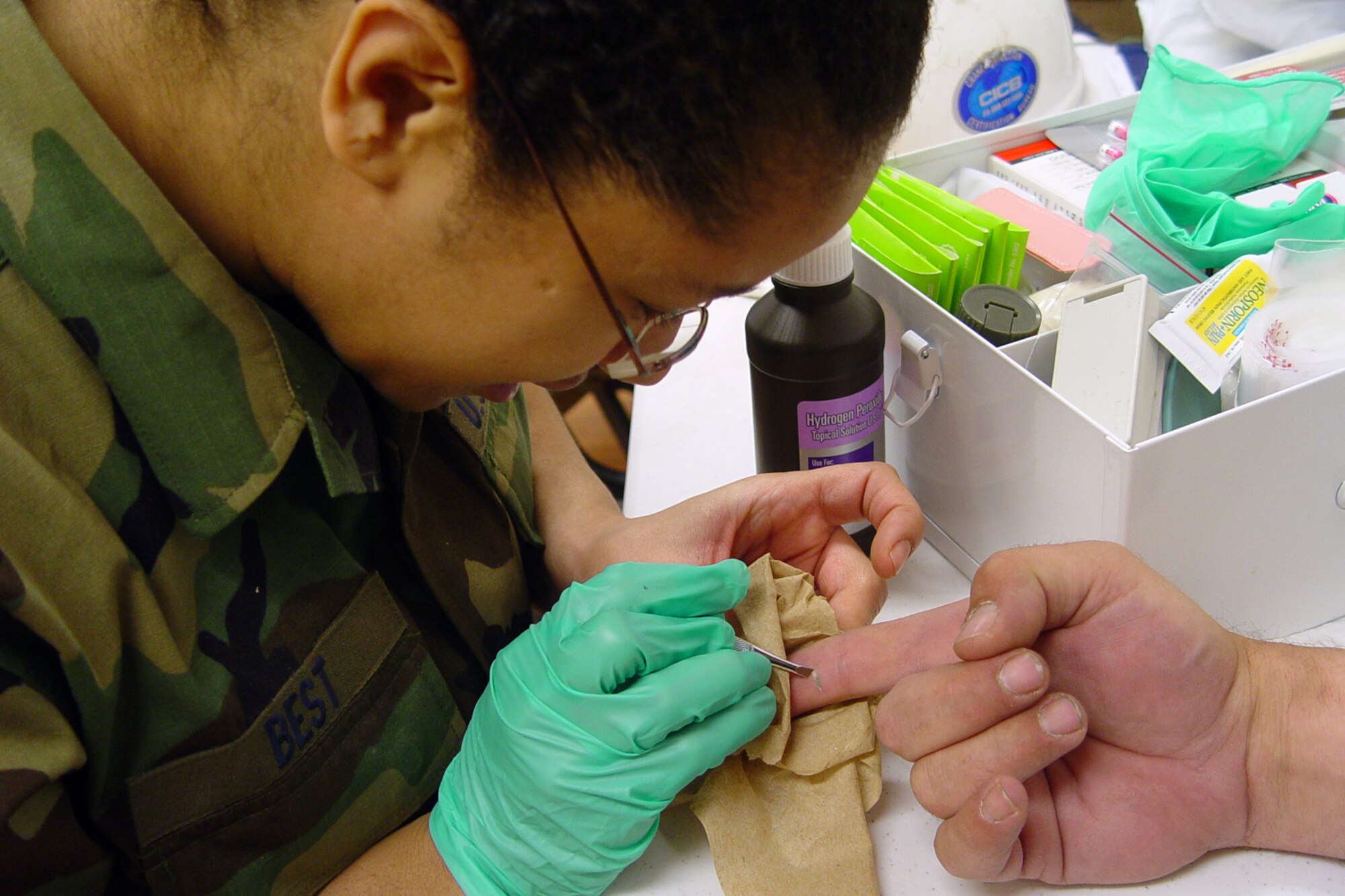 GALLUP, N.M. -- Senior Airman Trisha Best, an aerospace medical services technician, removes a splinter from the hand of a Grissom civil engineer. Members of the 434th Civil Engineers Squadron are in New Mexico to construct houses for Native Americans and hone their trade. The deployments lets the engineers get hands on training in a variety of areas both in and out of their specialties. (U.S. Air Force photo/Senior Master Sgt. Chuck Gill)