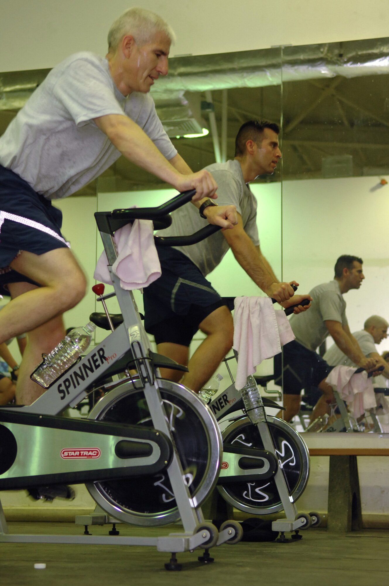 BALAD AIR BASE, Iraq -- Lt. Col. David Lujan, 332nd Expeditionary Operations Group deputy commander, and Tech. Sgt. Emmanuel Ramirez, 332nd Expeditionary Civil Engineer Squadron power production technician, work out on a stationary bike during a class at the Red Tail Fitness Center here, May 31. Maintaining a healthy, physically fit lifestyle helps Airmen to carry out their daily duties more efficiently in a deployed environment. Each person in the class can choose their own goals for the session. Some participants choose to maintain a moderate, aerobic intensity level, while others drive their heart rates higher in intervals of anaerobic activity. Sergeant Ramirez is deployed from Peterson Air Force Base, Colo. (U.S. Air Force photo/ Senior Airman Julianne Showalter)