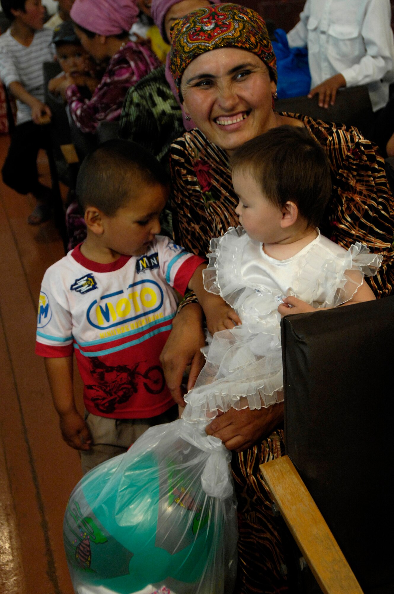 Less fortunate members of Oktyabrskoye village show their gratitude as their children receive gift bags from Airmen of the 376th Expeditionary Security Forces Squadron, Manas Air Base, Kyrgyz Republic, on May 30 as part of the village's recognition of International Protection Day, which is June 1. The Airmen delivered gift bags of hygiene products, T-shirts,  towels, candy, coloring books, toys, and other much needed supplies. The items were purchased with money allocated from the private organizations on base and with donations from home units of the security forces members. (U.S. Air Force Photo by Staff Sgt. Tabitha Kuykendall) (RELEASED) 