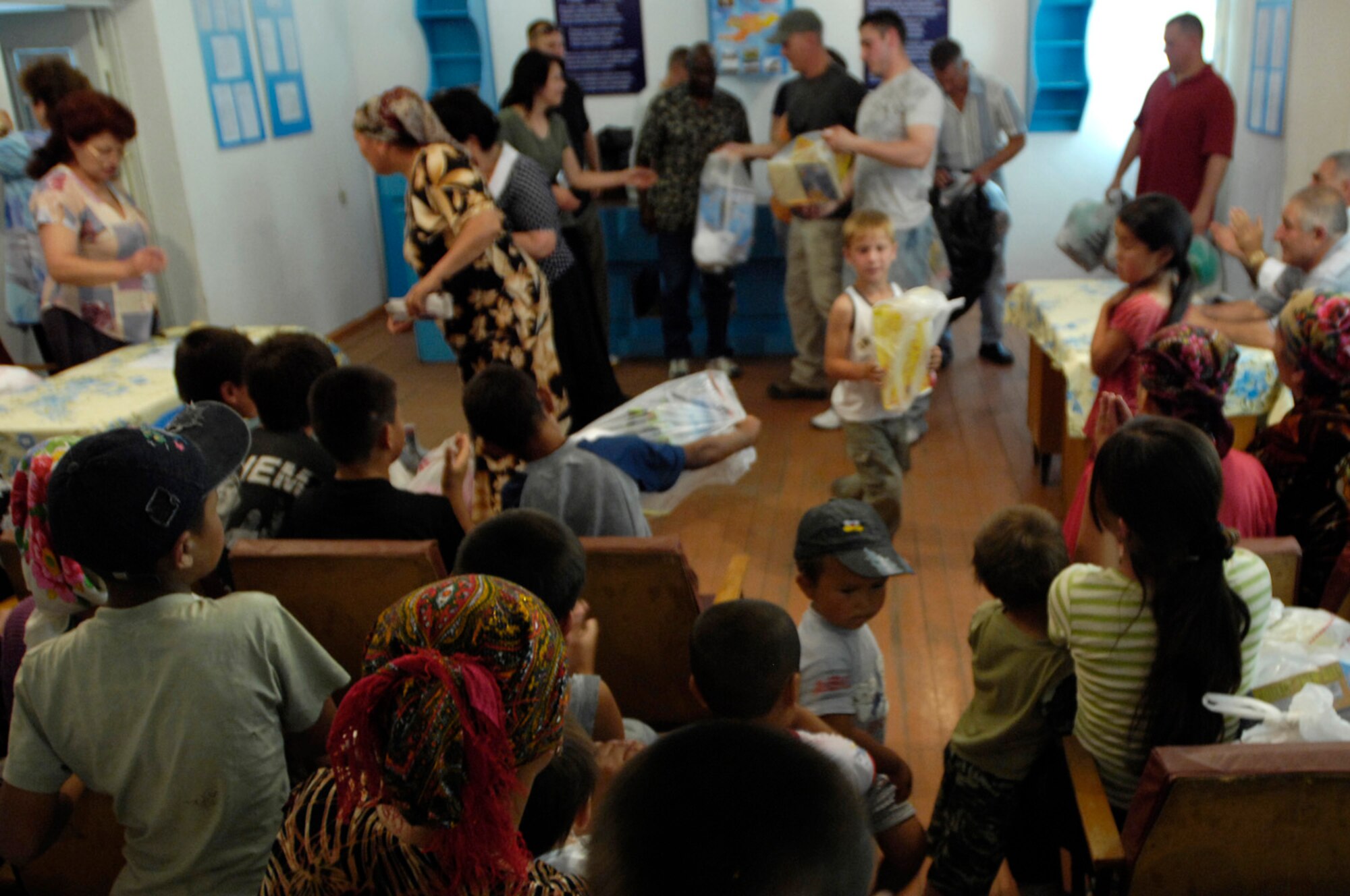 Airmen of the 376th Expeditionary Security Forces Squadron, Manas Air Base, Kyrgyz Republic, hand out gift bags to some of the less fortunate members of Oktyabrskoye village in recognition of International Protection Day, which is June 1. The gift bags included hygiene products, T-shirts,  towels, candy, coloring books, toys, and other much needed supplies.  The items were purchased with money allocated from the private organizations on base and with donations from home units of the security forces members. (U.S. Air Force Photo by Staff Sgt. Tabitha Kuykendall) (RELEASED) 