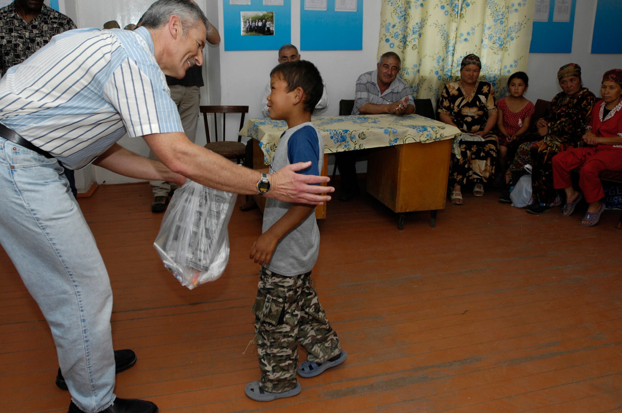 CMSgt Tim Tillman, 376th Expeditionary Security Forces Squadron, Manas Air Base, Kyrgyz Republic, hands out gift bags to some of the less fortunate members of Oktyabrskoye village in recognition of International Protection Day, which is June 1. The gift bags included hygiene products, T-shirts, towels, candy, coloring books, toys, and other much needed supplies.  The items were purchased with money allocated from the private organizations on base and with donations from home units of the security forces members. (U.S. Air Force Photo by Staff Sgt. Tabitha Kuykendall) (RELEASED) 
