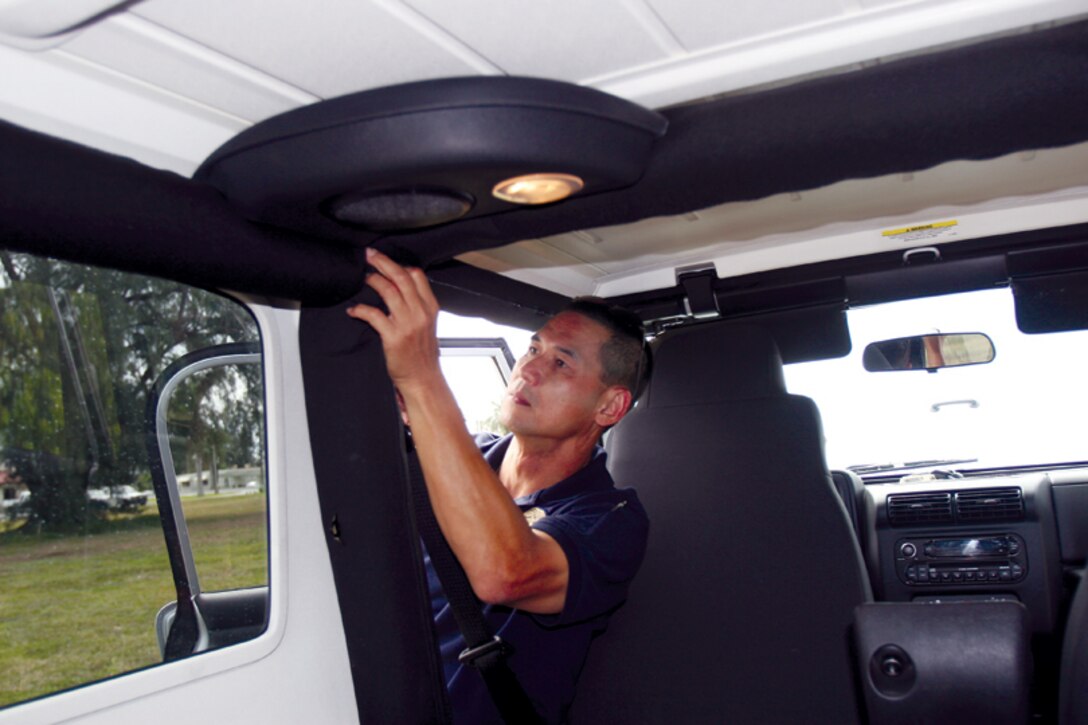 Kittinart Saneewong, trainee, Marine Corps Civilian Police Academy, inspects the inside of the vehicle while being a member of the search team during a practical applications class Friday. The trainees are taught how to search vehicles and where to look for anything suspicious.