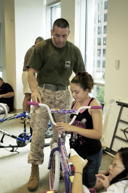Lucy Santoyo helps her father, Staff Sgt. Ray Santoyo of 4th Force Reconnaissance Company, assemble one of more than 100 bicycles donated by BAE Systems employees to the Marine Corps' annual Toys for Tots program. More than 65 employees, family members, Marines and their families donated their time to assemble these bikes Saturday morning.