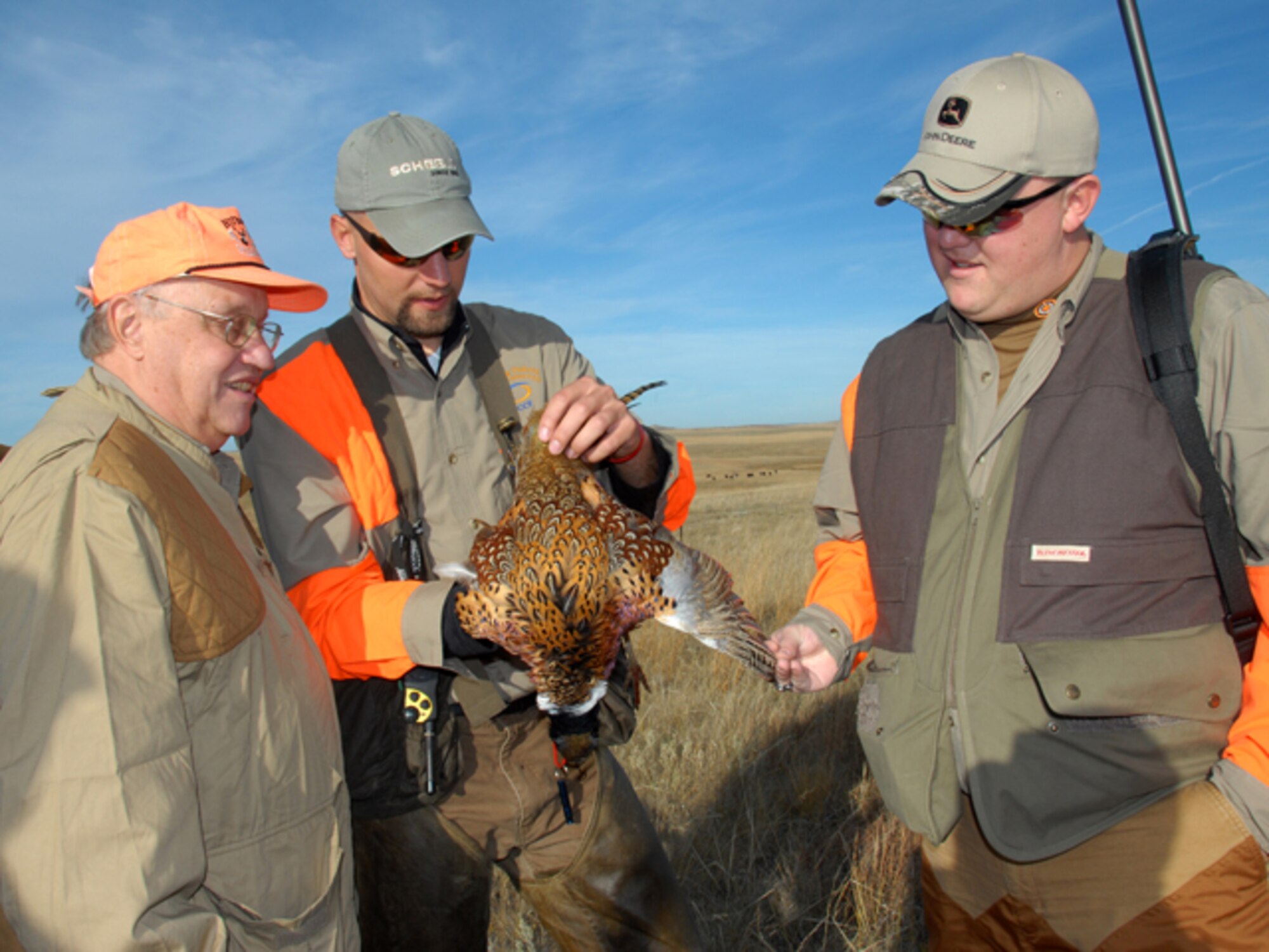 From left to right, Tweed Roosevelt, the great-grandson of twenty-sixth President of the United States Theodore Roosevelt, hunting-dog handler Benjamin Sand, of Bismarck, and Spc. Nathan McGough, of the 231st Brigade Support Battalion, admire a rooster pheasant during the Hunting Dakota with Roosevelt hunt Oct.18 south of Mandan, N.D. McGough beams with pride as the first successful marksman of the day.