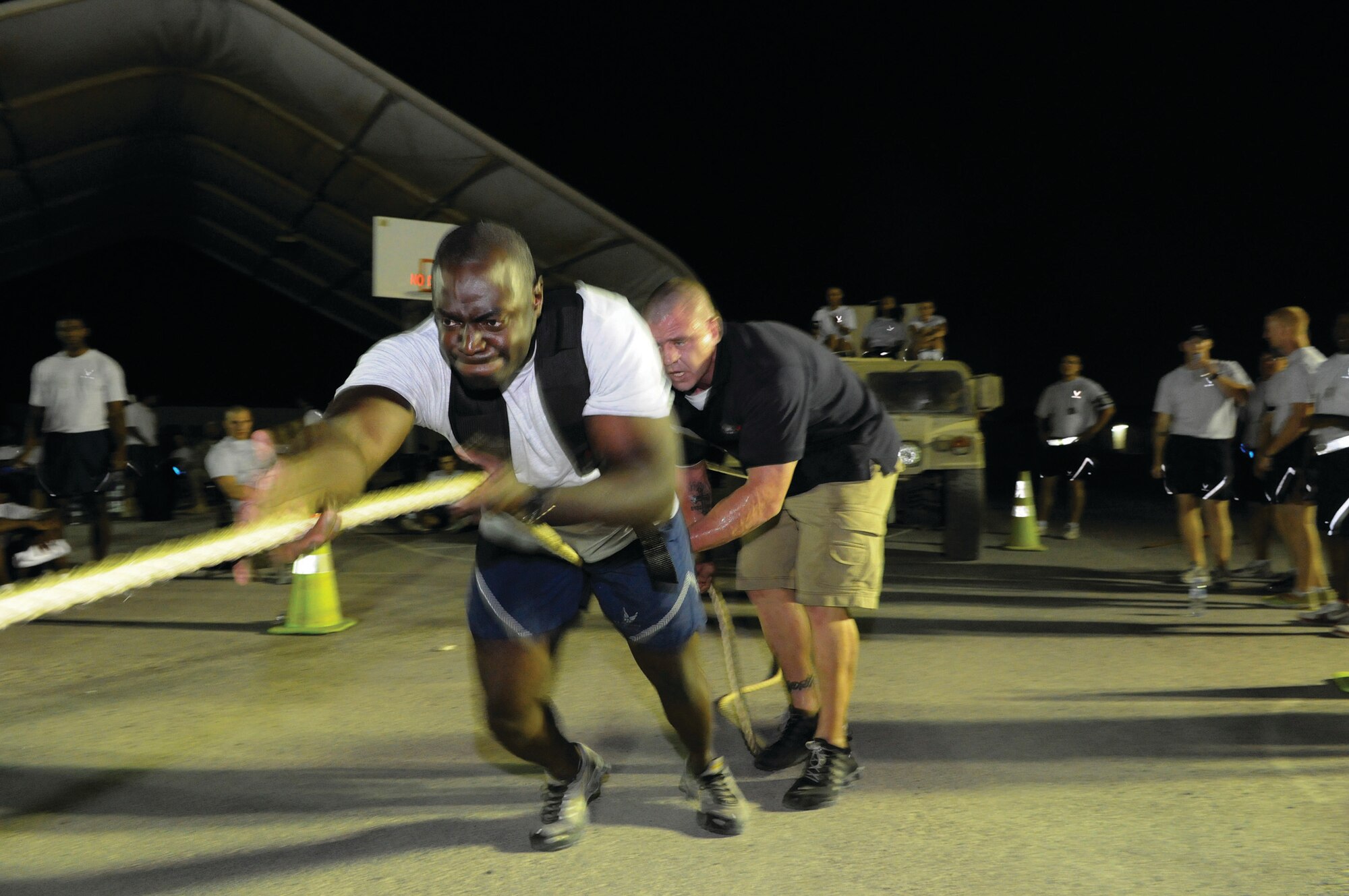 Staff Sgt. Sean Fishburne, 379th Expeditionary Logistics Readiness Squadron, competes in the High Mobility Multi-purpose Wheeled Vehicle pull during the Strong Man/Strong Mind Challenge at an undisclosed location in Southwest Asia Oct. 25, as Chris Tyler, Blatchford-Preston Complex fitness supervisor, keeps the tension tight on the anchor rope. (U.S. Air Force photo by Tech. Sgt. Michael Boquette)
