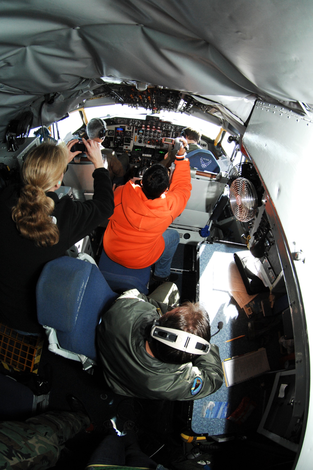 Dessie Sudberry (top middle), takes photos behind the cockpit of a KC-135 Stratotanker while Master Sergeant Johnny White (bottom right), boom operator with the 171st Air Refueling Squadron, observes. The flight served to familiarize 127th Air Refueling Group spouses with the new air refueling mission of the 127th Wing. (U.S. Air Force photo by Senior Airman Jeremy L. Brownfield) (Released)
