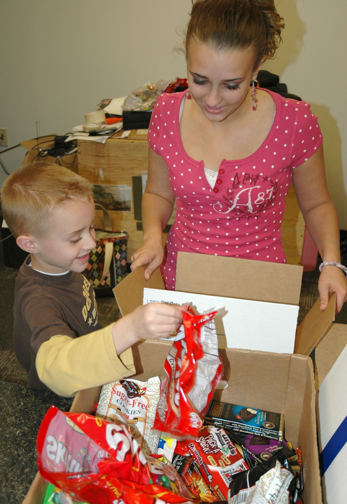 Nine-year-old Ethan Thomas is helped by his sister, Nina, as he picks out goodies for packing Nov. 1 during the Key Family Member Program's deployment care package drive at the 39th Aerial Port Squadron at Peterson Air Force Base, Colo. The packages were assembled by volunteers for members of the 302nd Airlift Wing deployed throughout Southwest Asia. Ethan and Nina's father, Tech. Sgt. Aaron Thomas, is deployed to Iraq from the 302nd Security Forces Squadron. (U.S. Air Force photo/Senior Airman Stephen Collier)