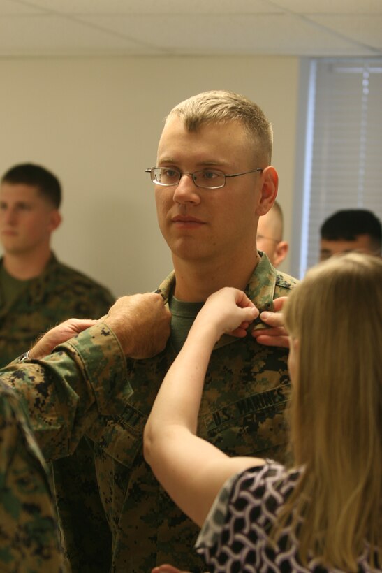 Sergeant Justin Burkett, a chemical, biological, radiological, and nuclear defense specialist with Headquarters Battalion, 2nd Marine Division, gets promoted by his wife and a fellow Marine after winning a meritorious sergeant board Oct. 24.  Burkett wants to re-enlist and be an instructor at his military occupational specialty school in Fort Leonard Wood, Mo.