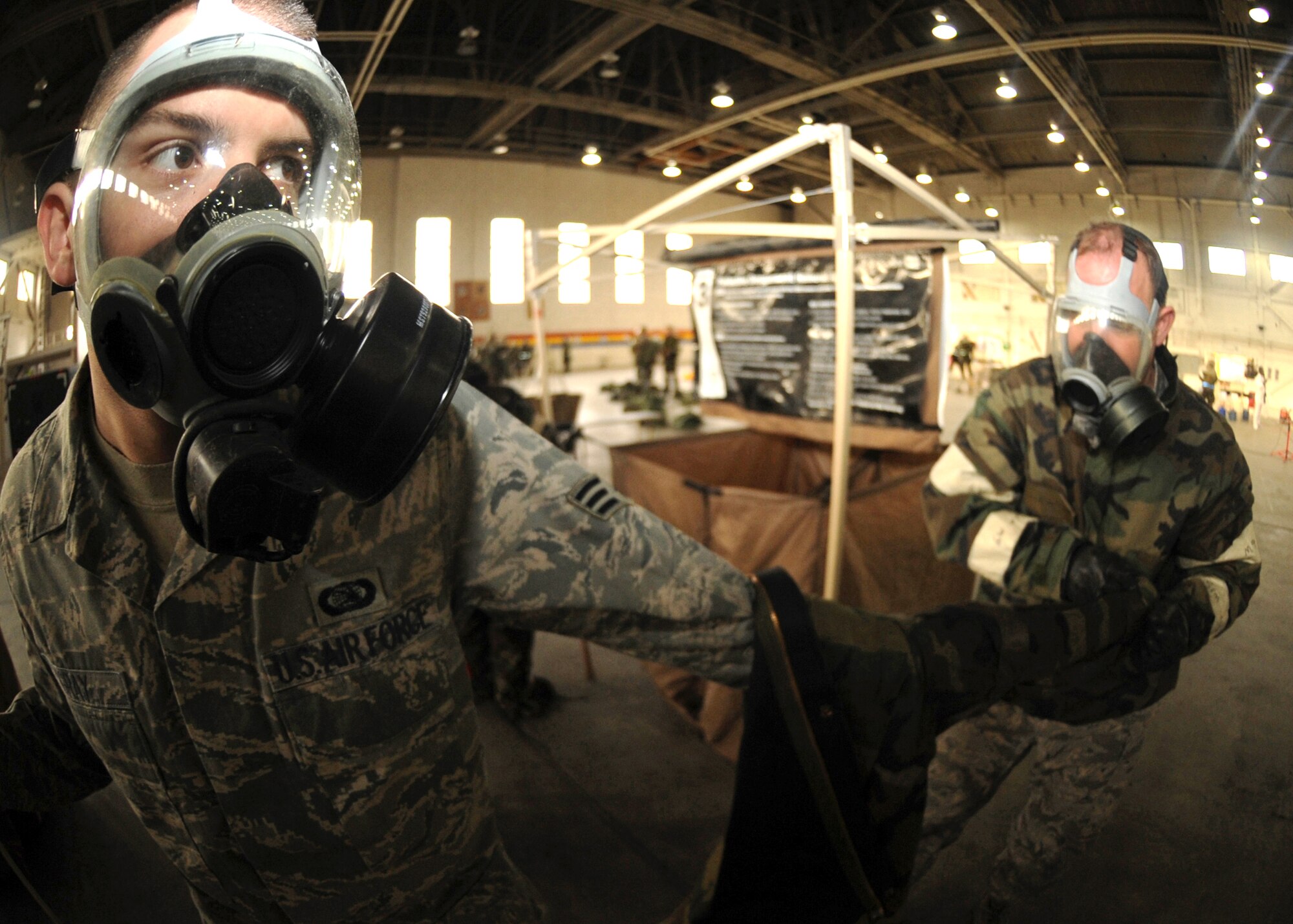 ELMENDORF AIR FORCE BASE, Alaska -- Tech. Sgt. Bryan Nelson, 3rd Equipment Maintenance Squadron, helps Senior Airman Michael Gray, 3rd Communications Squadron, remove his chemical overgear during the Polar Force 09-1 exercise Oct. 30. This aircrew decontamination scenario took place in Hangar 5 during the three-day exercise. (U.S. Air Force photo/Senior Airman Matthew Owens)