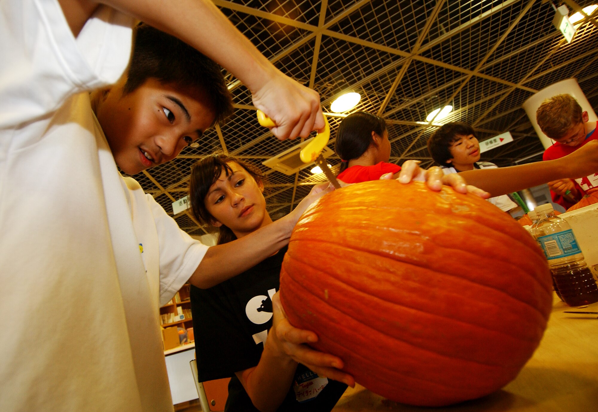 Ryousuke Shimabukuro,12, receives help carving a pumpkin from Taylor Hadden, 13, during a cultural exchange November 2, 2008 at the Okinawa Zoo. Members of Kadena's Club Zero and Japanese students  participated in various activities throughout the day during Pumpkin Palooza. (U.S. Air Force photo/Tech. Sgt. Rey Ramon)            