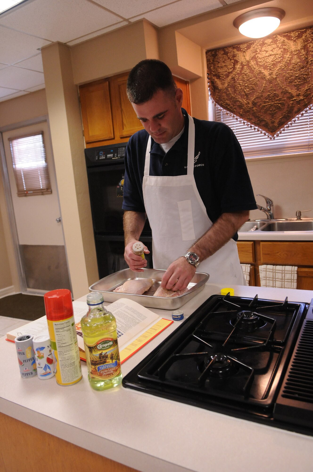 Air Education and Training Command Junior Enlisted Aide of the Year, Tech. Sgt. Jason Barbour, works on a meal of baked chicken on at the home of 19th Air Force Commander Gen. Gregory Feest recently. (U.S. Air Force photo by Rich McFadden)
