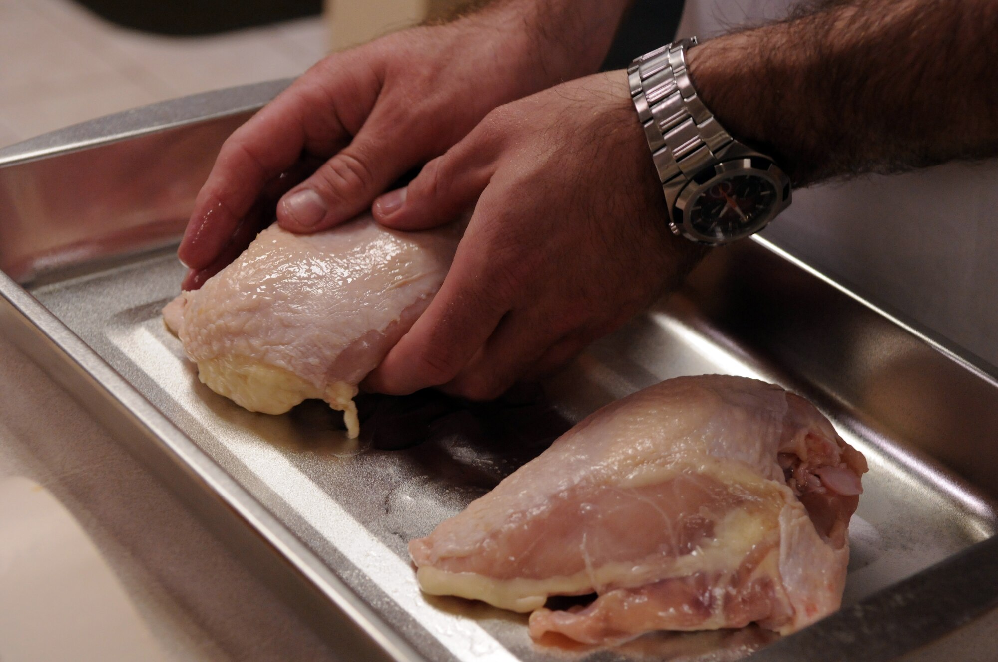 Air Education and Training Command Junior Enlisted Aide of the Year, Tech. Sgt. Jason Barbour, begins preparations of meal of baked chicken at the home of 19th Air Force Commander Gen. Gregory Feest recently. (U.S. Air Force photo by Rich McFadden)