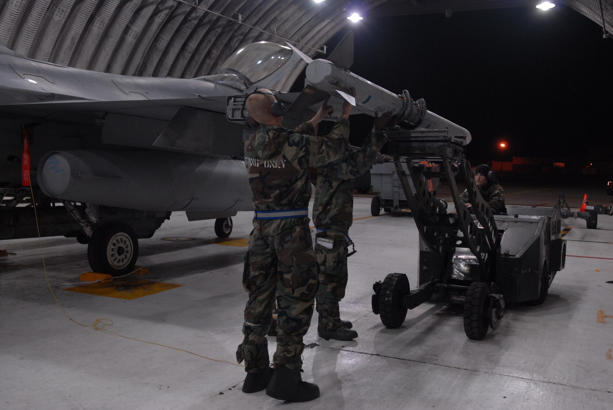Airman 1st Class Corey Radel, Senior Airman Brianne Brown and Airman 1st Class Joshua Hnatiuk, 8th Aircraft Maintenance Squadron, load a weapon onto the F-16 Fighting Falcon during a peninsula-wide Operational Readiness Exercise Beverly Bulldog 08-04 at Kunsan Air Base, Republic Of Korea, Nov. 4, 2008. Airmen participating in the PENORE will be tested on their wartime capabilities and response actions in order to complete the Wolf Pack mission. (U.S. Air Force photo by: Senior Airman Angela Ruiz/RELEASED by MSgt John Foster)