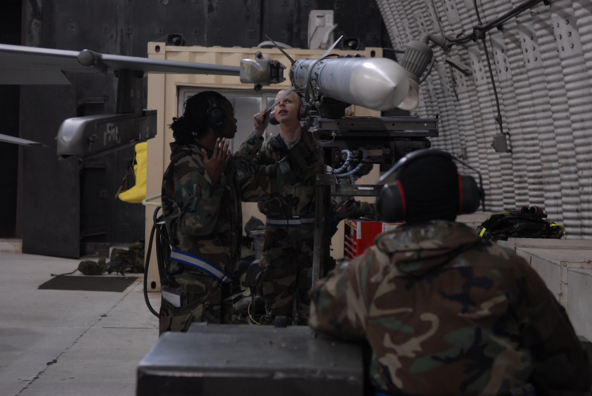 Senior Airman Brianne Brown uses her hands to communicate with Airman 1st Class Corey Radel while Airman 1st Class Joshua Hnatiuk holds the weapon being loaded to a F-16 Fighting Falcon during a peninsula-wide Operational Readiness Exercise Beverly Bulldog 08-04 at Kunsan Air Base, Republic Of Korea, Nov. 4, 2008. Airmen participating in the PENORE will be tested on their wartime capabilities and response actions in order to complete the Wolf Pack mission. (U.S. Air Force photo by: Senior Airman Angela Ruiz/RELEASED by MSgt John Foster)
