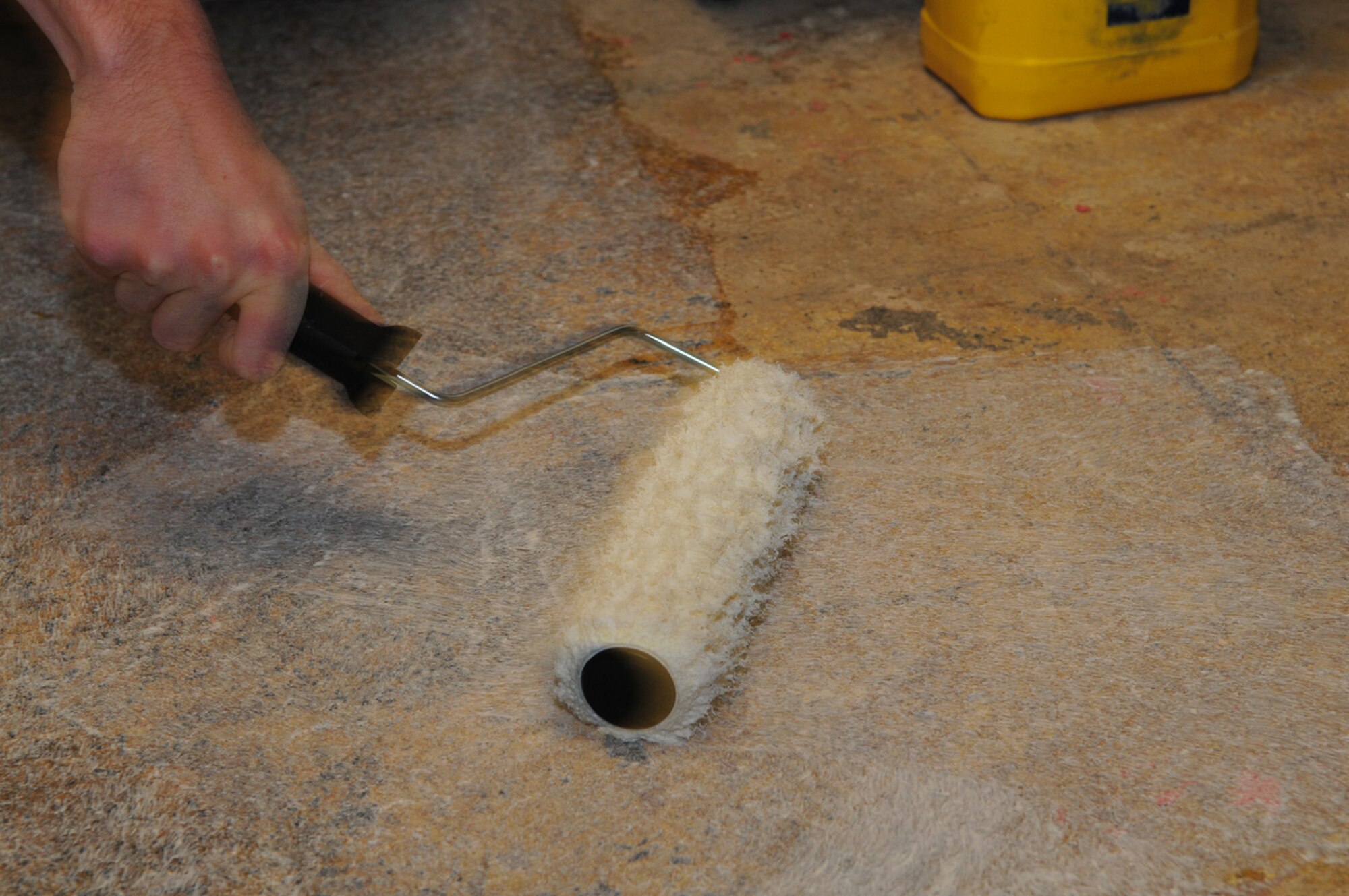 Airman Cody Seymour, from the 100th Civil Engineer Squadron Structural Shop, applies glue to an area of the floor in the small kitchen area of the 100th Air Refueling Wing headquarters building Oct. 29, before carpet tiles are laid. Personnel from the structural shop maintain buildings around base and are responsible for work such as replacing doors and repairing roof leaks. (U.S. Air Force photo by Karen Abeyasekere)