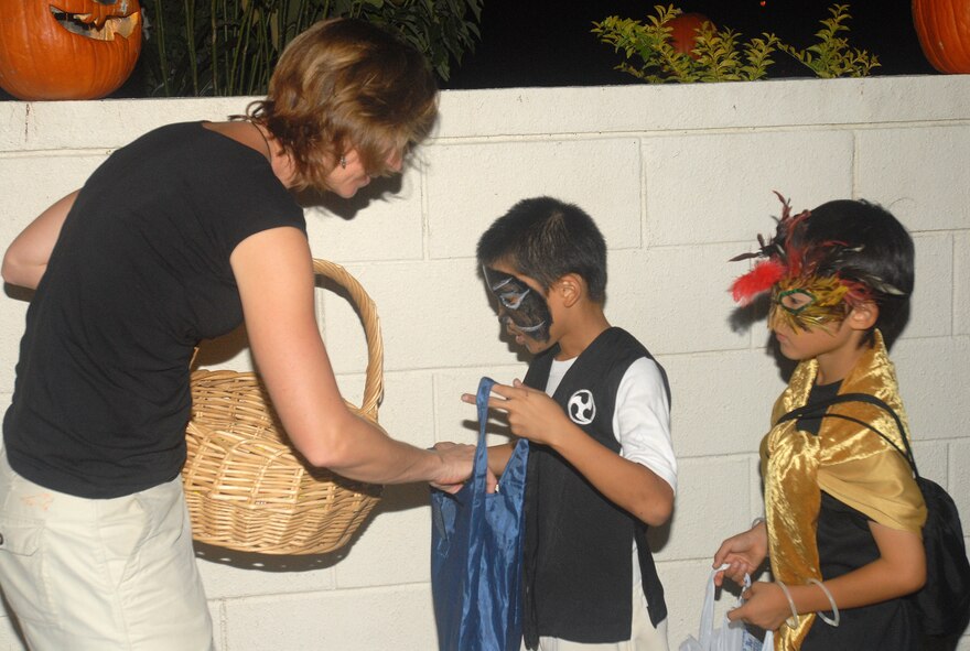 Pam Gabriel, wife of Maj. Daniel Gabriel, 18th Dental Squadron, passes out candy to colorfully dressed Okinawan children Oct. 31. SOFA-status personnel invited their Okinawan friends for an evening of trick-or-treating fun around Kadena housing areas.
(U.S. Air Force official photo/Staff Sgt. Nestor Cruz)
