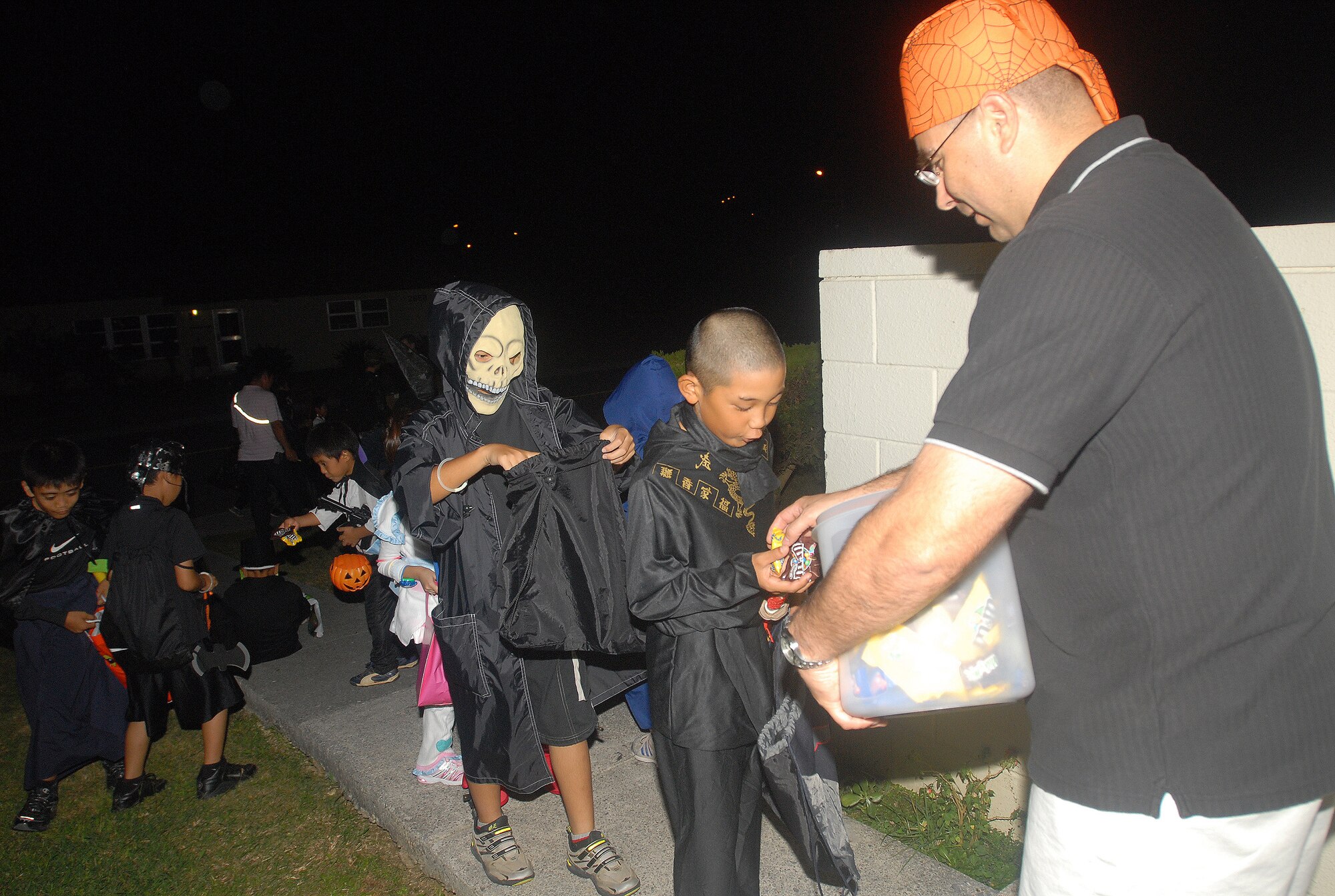 Okinawan children dressed as ghouls, ninjas and superheroes receive candy from a Kadena resident Oct. 31. SOFA-status personnel sponsored their Okinawan friends for an evening of trick-or-treating fun in Kadena housing areas. (U.S. Air Force official photo/Staff Sgt. Nestor Cruz)