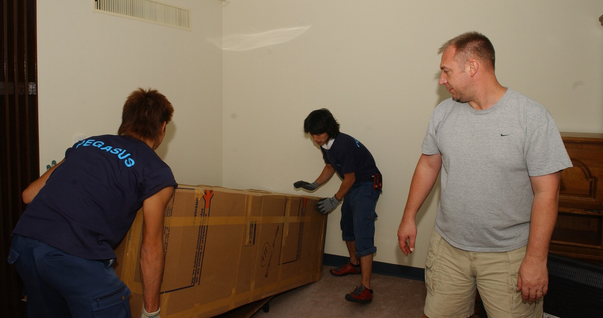 Senior Master Sgt. Timothy Petersen, 374th Airlift Wing command post, watches as Mr.Tagima Hiroki and Mr. HIde Takahashi moves his funiture into his new home. (U.S. Air Force photo by Airman 1st Class Eric Summers)                 