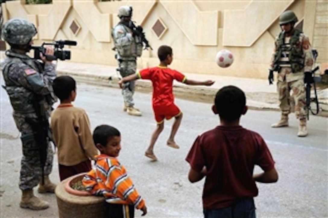 An Iraqi boy shows off his soccer skills for U.S. and Iraqi troops conducting a patrol in Al Muhandiseen, Iraq, Oct. 30, 2008. U.S. Air Force Tech. Sgt. Adrienne Brammer, left, of the 1st Combat Camera Squadron, captured the moment on video.